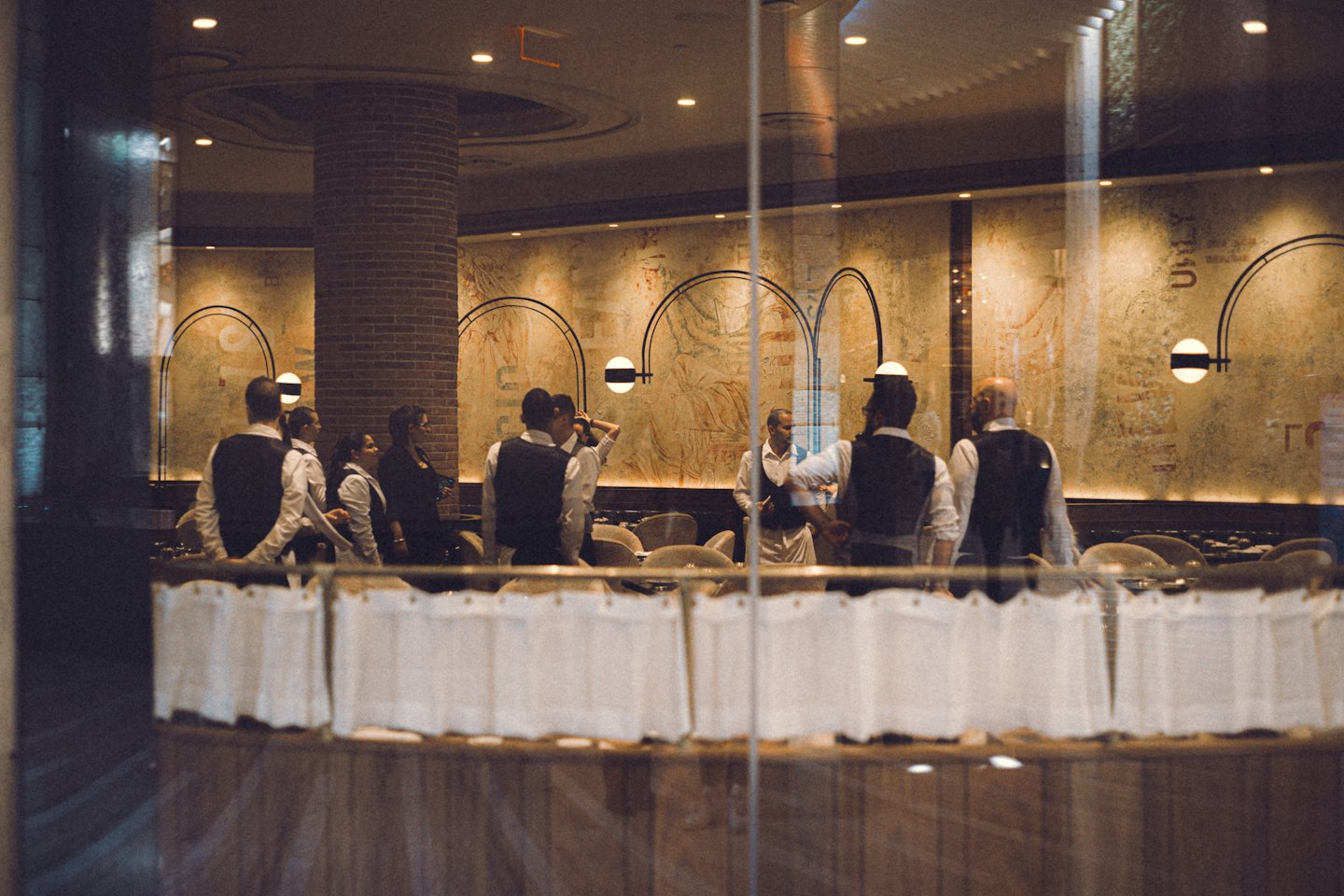 Il personale del ristorante si riunisce per un briefing pre-servizio nella sala da pranzo.