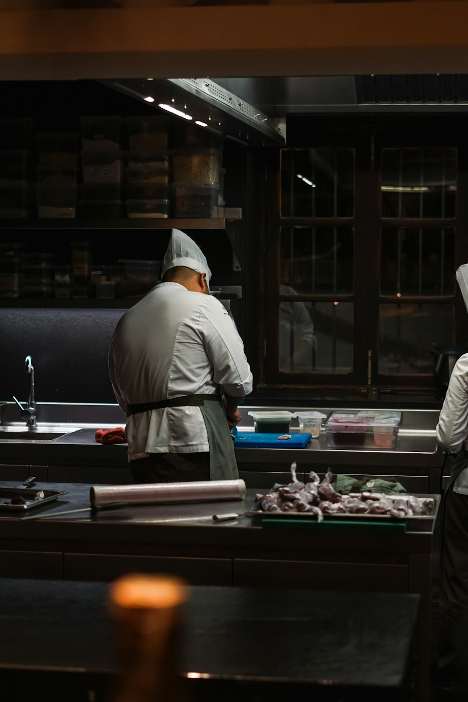 Chef in divisa bianca prepara cibo in una cucina affollata.