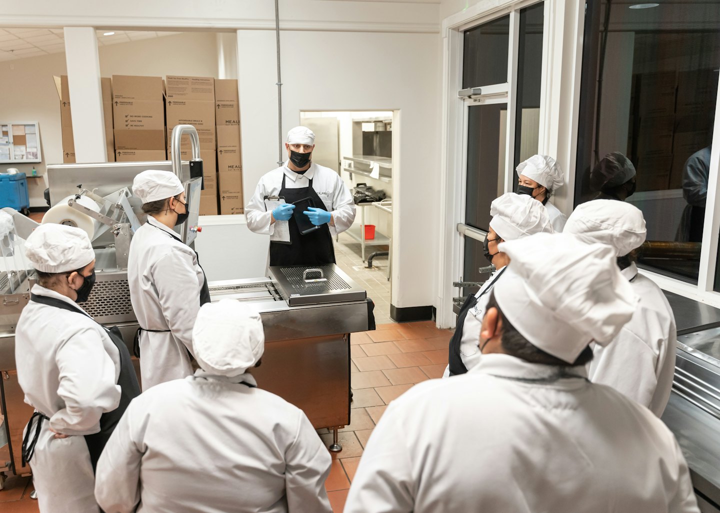 Un istruttore guida una sessione di formazione per il personale in una cucina industriale.