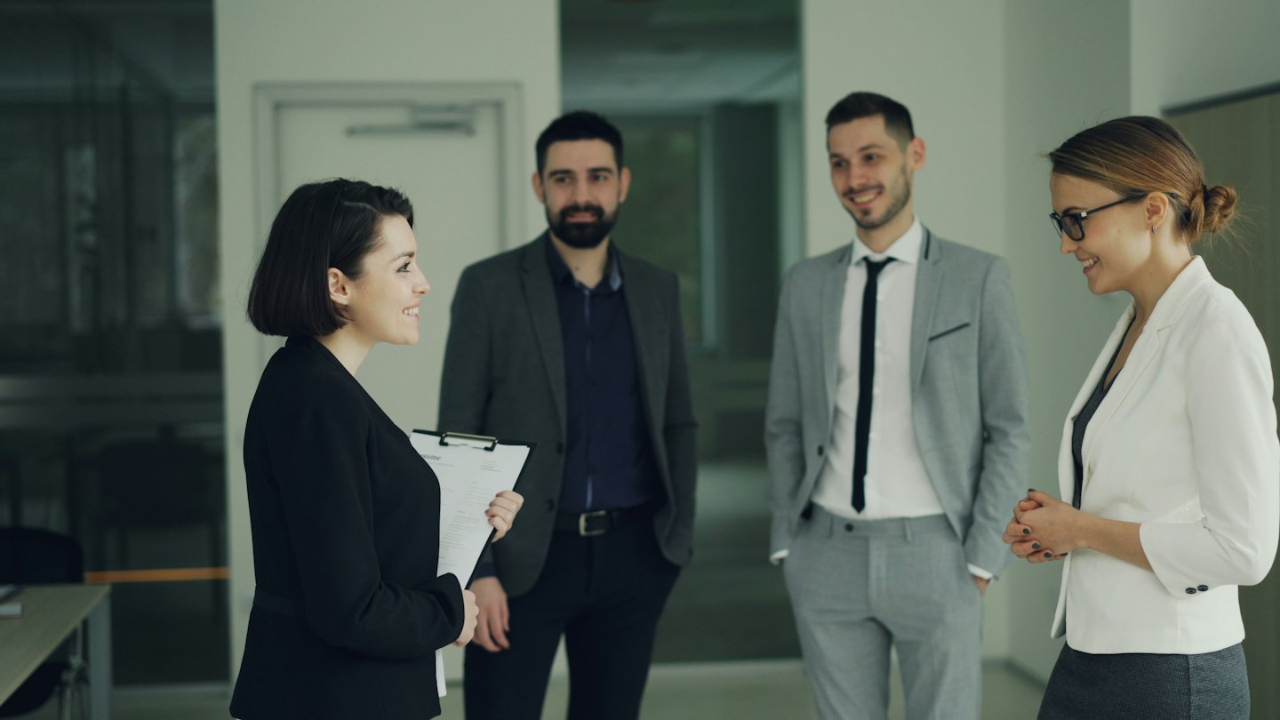 Professionisti aziendali che discutono idee in un moderno corridoio d'ufficio.