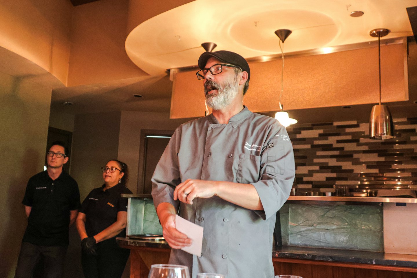 Chef che istruisce due membri dello staff attenti in un ristorante.